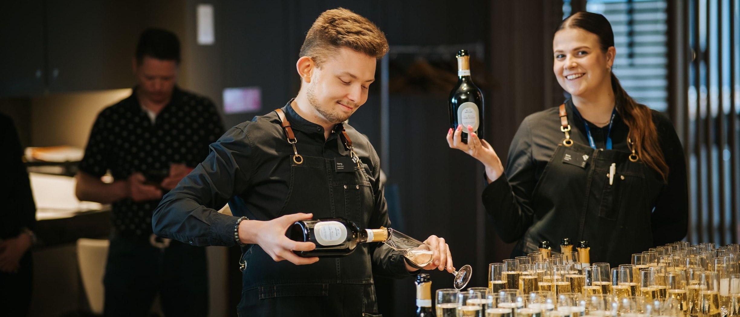 Two waiters pouring champagne into glasses